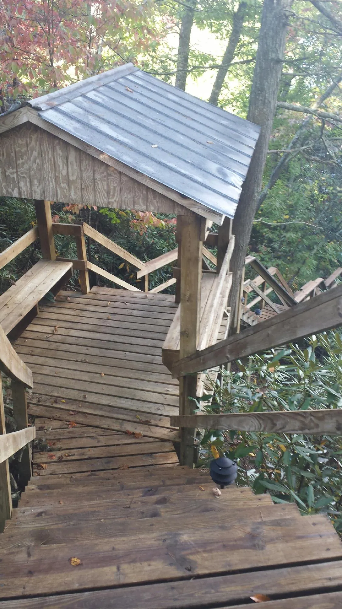 Metal roofed shelter over wooden steps on a wooded walkway — Skylight Repair & Installation work by our crew in Iola